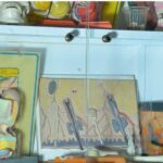 کابینت نمایشی شامل مدل‌های آناتومی دندان، نقاشی‌های آموزشی دانش‌آموزان، و ابزارهای علمی روی قفسه‌های سفید و رنگی
