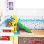 اتاق کلاس درس کودکان با تجهیزات بازی، سلاید رنگی، و دیوارهای تزیین‌شده با نقاشی‌های کودکان