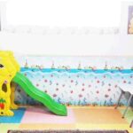 کلاس درسی مجهز به سرسره سبز و زرد، میز‌های کودک و صندلی‌های رنگی با دیوارهای تزیین‌شده به نقاشی‌های آموزشی و فارسی