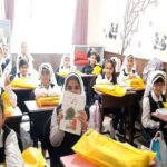 دانش‌آموزان دختر در کلاس درس به هنگام فعالیت درسی با کتاب‌های زرد و نقاشی‌های رنگی دیوار