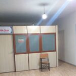 قاعة الصلاة في المدرسة مع أرضية خشبية وكراسي وإضاءة بسيطة