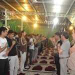 تجمع دانش‌آموزان و معلمان در سالن مدرسه برای برگزاری یک مراسم و رویداد جمعی