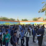 جمع‌آوری دانش‌آموزان در حیاط مدرسه برای شرکت در مراسم و رویداد مدرسه‌ای با دیوار رنگارنگ