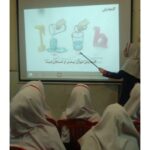دانش‌آموزان در حال تماشای درس تعاملی روی صفحه‌نمایش در کلاس درس، با نمایش محتوای آموزشی و انیمیشن‌های درسی