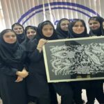 گروهی از دانش‌آموزان دختر در حال نمایش اثر هنی نقش‌برجسته‌ی سیاه و سفید در کلاس درس