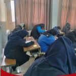 تعدادی از دانش‌آموزان دختر و پسر در حال نشستن در کلاس درس بر روی میزهای امتحان، در حال پاسخ دادن به سوالات تست کتبی و حل نمونه سوالات