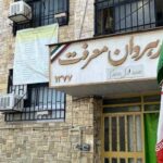 نمای ساختمان راهوان شریف با درب ورودی و تابلوی نام، دو پرچم ایرانی در دو طرف ورودی