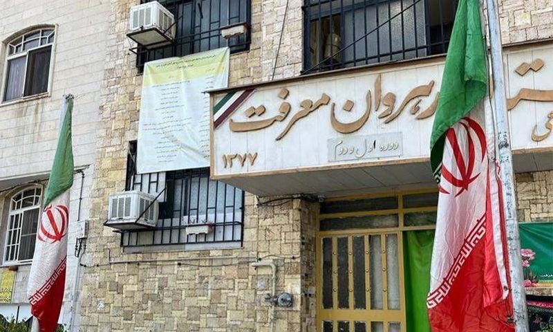 نمای ساختمان راهوان شریف با درب ورودی و تابلوی نام، دو پرچم ایرانی در دو طرف ورودی