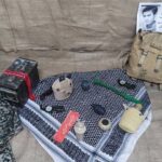 نمایشگاه تاریخی در مدرسه با تجهیزات کمپینگ قدیمی، عکس شخصی فارسی‌نویس، پرچم ایران و اشیای یادبودی روی سطح نمایش