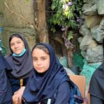 دانش‌آموزان دختری در حال انجام فعالیت پروژه‌ای محیطی با گیاهان و سنگ‌ها در فضای باز مدرسه