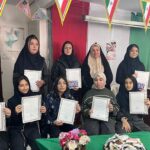 دختران دانش‌آموز در حال نمایش گواهینامه‌های اهدایی در مراسم داخل مدرسه با تزیینات و تابلوی دیواری
