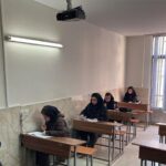 کلاس درسی با دانش‌آموزان در حال نوشتن و مطالعه، داشتن تخته‌سفید، تابلو نور و پروژکتور سقفی