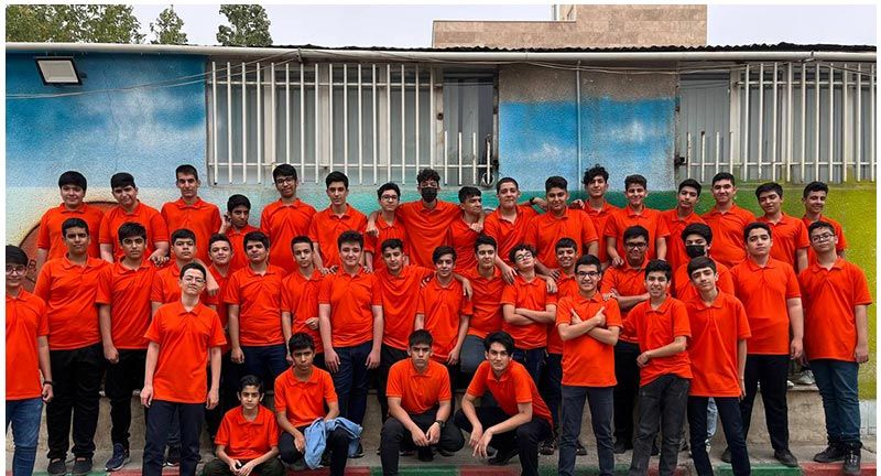 گروهی از دانش‌آموزان در لباس قرمز در حیاط مدرسه جمع‌شده‌اند