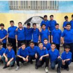 گروه دانش‌آموزان پسر در لباس ورزشی آبی ایستاده در حیاط مدرسه برای عکس یادگیری گروهی
