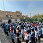 دانش‌آموزان یونیفرم‌پوش در حیاط مدرسه در حین تجمع و شرکت در یک فعالیت مدرسه‌ای