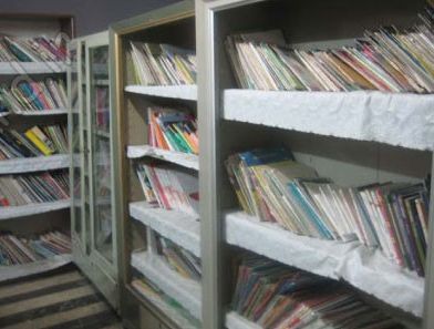 قفسه‌های کتابخانه‌ی مدرسه با کتاب‌های درسی و علمی متنوع رنگین در ردیف‌های منظم