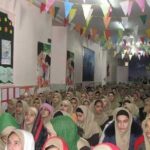 تجمع دانش‌آموزان و دختران در یک سالن با تزئینات رنگی و روبان‌های رنگارنگ، در حین برپایی مراسمی دانش‌آموزی