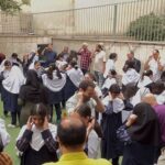 تجمع دسته‌جمعی از دانش‌آموزان و معلمان در حیاط مدرسه به‌مناسبت برگزاری یک مراسم یا رویداد دانش‌آموزی