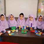دانش‌آموزان دختر در کلاس درس در حال انجام فعالیت ساخت‌وساز با قطعات LEGO رنگی