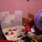 دانش‌آموزان در حال انجام فعالیت‌های آموزشی و سازمان‌دهی مواد با جعبه‌های پلاستیکی در کلاس درس