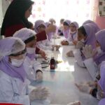 دانش‌آموزان دختر در کلاس درس اثناء انجام فعالیت عملی و هنری تحت نظارت معلم