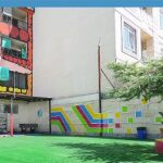 محیط حیاط مدرسه با دیوار هنری رنگارنگ و المان‌های سبز