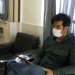 معلم یا مربی نشسته در کلاس درس با لپ‌تاپ، در حال برگزاری جلسه آموزشی یا تدریس فردی به دانش‌آموز