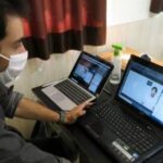 دانش‌آموزی در حال کار و یادگیری روی دو لپ‌تاپ در محیط آموزشی
