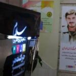 راهروی مدرسه با صفحه‌نمایش الکترونیکی و پوستر یادبود شهید