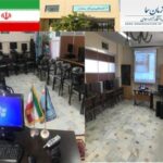 نمای عمومی سایت کامپیوتر مدرسه با میزهای کامپیوتری، صفحات نمایش و صندلی‌های سیاه در کنار پنجره‌های روشن