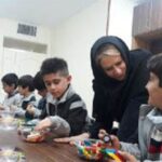 دانش‌آموزان در حال کار مشترک با لگو و قطعات ساختمانی تحت راهنمایی معلم در کلاس درس