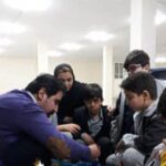 دانش‌آموزان در حال شرکت در یک فعالیت آموزشی گروهی در کلاس درس با نظارت معلم