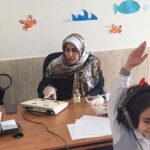جلسه درس تعاملی و سوال‌پاسخ در کلاس درس با معلم و دو دانش‌آموز در حال بحث و یادگیری