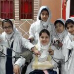 گروهی از دانش‌آموزان دختر با حجاب سفید در حال انجام فعالیت یا رویداد گروهی در حیاط مدرسه