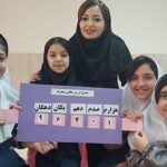 گروهی از دانش‌آموزان در حال ارائه‌ی پروژه خود با یک پوستر آبی رنگ درون کلاس درس