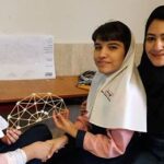 سه دانش‌آموز درحال کار روی یک ساختار هندسی سه‌بعدی ساخته‌شده از میله‌ها در یک فعالیت عملی STEM کلاسی