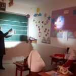 کلاس درس مدرسه‌ای با تخته‌سیاه سبزرنگ، دیوارهای صورتی و تزیینات رنگین از ستاره و عناصر دیگر