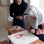دو دانش‌آموز در حال انجام یک پروژه تحقیقی با ساخت دستگاه و طراحی آن روی کاغذ