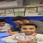 دانش‌آموزان در حال شرکت در یک فعالیت یادگیری عملی در کلاس درس، با حضور معلم و در حال کار با مواد آموزشی