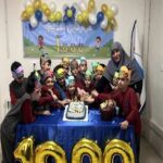 عکس جشن تولد دانش‌آموزان در کلاس با کیک و بادکنک‌های طلایی و آبی و تجهیزات جشن