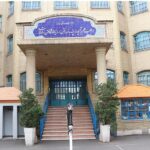درب ورودی اصلی مدرسه با تابلوی نام فارسی دائمی بر روی معماری ستون‌دار و پله‌های ورودی سنگی