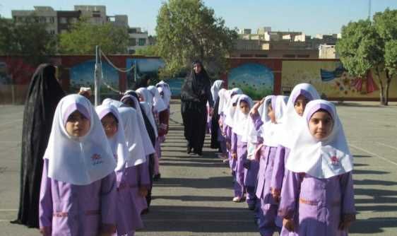 دانش‌آموزان دختر با لباس فرم بنفش و پوشش سفید در یک تجمع منظم‌شده‌ی رسمی در حیاط مدرسه
