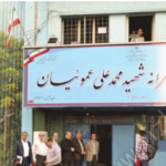 درب ورودی و نمای بیرونی ساختمان مدرسه با تابلوی نام پیشتازان پرسرائت شهید محمدی علی عسکریان و پرچم ایران