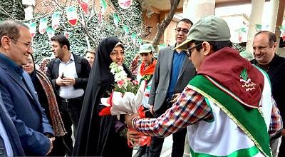 عکس مراسم تکریم و تجلیل دانش‌آموز برگزیده در حضور مسئولان و اساتید مدرسه، با روبان سبز و گل‌های قرمز و سفید