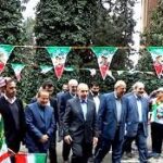 گروهی از مسئولین و دانش‌آموزان مدرسه در حین یک مراسم رسمی با بنرهای تزیینی ملی