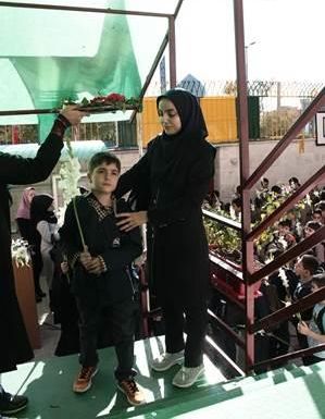 پسری و یک معلم در حال انجام فعالیت عملی در حیاط مدرسه، زیر سایبان سبز