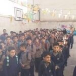 تجمع دانش‌آموزان مدرسه شاهد مطهری در یک مراسم یا رویداد دسته‌جمعی در فضای داخلی مدرسه