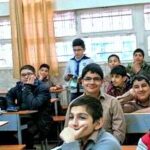 دانش‌آموزان و معلم در کلاس درسی با تخته سفید و جداول آموزشی