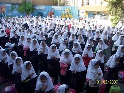 تجمع دستجمعی دانش‌آموزان دختر با لباس یکسان و حجاب در فضای بیرونی مدرسه