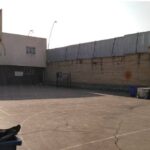 حیاط خارجی مدرسه با کف سیمانی، سقف سبز و سبد بسکتبال